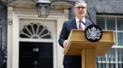 Sir Keir Starmer - a man wearing a dark suit and red tie - stands at a lectern with the government crest on it outside No 10 Downing Street