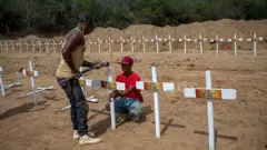 Uma pessoa colocando uma cruz no cemitério