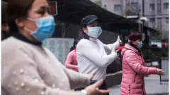 Một nhóm phụ nữ đeo khẩu trang tập dưỡng sinh tại Vũ Hán hôm 27/1