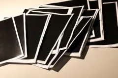 ページが全て黒塗りされた資料の紙がたくさん机の上に並んでいる