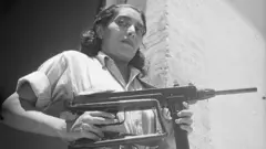 Una mujer sostiene un arma.