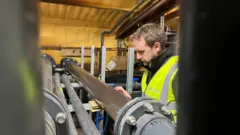 Tom Bell observando uma tubulação que transporta água para a instalação em Weymouth