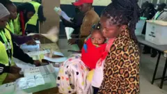 Umugore urimo gutora akikiye umwana we, mu mujyi wa Nakuru mu karere ka Rift Valley, mu burengerazuba bwa Kenya 