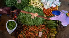 A customer buys vegetables at a market in Colombo on March 21, 2023.