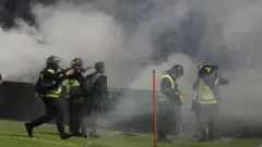 Aparat keamanan menembakkan gas air mata untuk menghalau suporter yang masuk lapangan usai pertandingan sepak bola BRI Liga 1 antara Arema melawan Persebaya di Stadion Kanjuruhan, Malang, Sabtu (1/10/2022). 