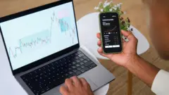 Trader is analyzing charts on his laptop and smartphone app, working remotely from his home office
