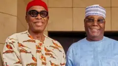 Chibuike Amaechi dey shake hand wit Atiku Abubakar as dem pose face camera.
Amaechi wear red cap with flowered cream colour cloth while Atiku wear sky blur cloth wit bue cap wey dey design.