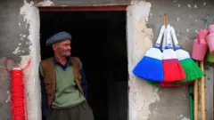 2009 yılında Mahmur kampında çekilmiş bir fotoğrafta bir adam bakkal dükkanının önünde ayakta görülüyor. 