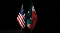 یکی از کارکنان، پرچم ایران را پس از گرفتن عکس گروهی با وزیران خارجه و نمایندگان ایالات متحده، ایران، چین، روسیه، بریتانیا، آلمان، فرانسه و اتحادیه اروپا در جریان مذاکرات هسته‌ای ایران در مرکز بین‌المللی وین، از روی صحنه برمی‌دارد. این عکس در ۱۴ ژوئیه ۲۰۱۵ گرفته شده است؛ روزی که ایران و شش قدرت بزرگ جهانی به توافق هسته‌ای دست یافتند. توافقی که پس از بیش از یک دهه مذاکرات پراکنده حاصل شد. (عکس از کارلوس باریا، خبرگزاری فرانسه)