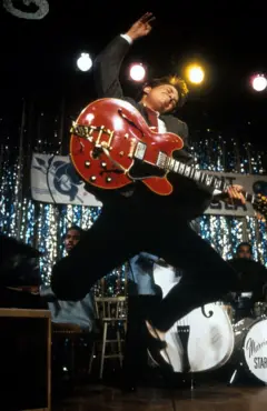 Michael J. Fox con guitarra eléctrica saltando en imagen de la película