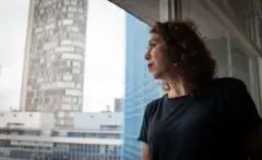 Maira na janela de seu apartamento no Copan olha a paisagem