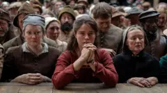 Cena do filme 'Hamnet: A Vida Antes de Hamlet", com a personagem de Jessie Buckley na primeira fila de um teatro lotado