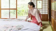 Uma mulher arrumando um futon na cama