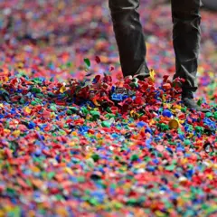 Pessoa caminha sobre uma espessa camada de fragmentos plásticos coloridos
