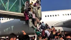 Pessoas se penduram a avião em Cabul