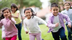 Niños corriendo en un parque.