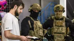 Mladić sa pasošem u ruci dok su pored njega dva vojnika