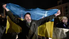 Seorang pria membentangkan bendera Ukraina di Lapangan Maidan, Kyiv, untuk merayakan pembebasan Kherson, pada 11 November 2022. 