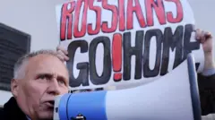 Николай Статкевич с мегафоном на фоне плаката "Русские, домой!"