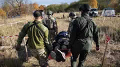 Четверо військових несуть пʼятого, імітуючи евакуацію пораненого 