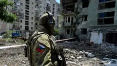 Un militar ruso patrulla una zona residencial destruida en la ciudad de Severodonetsk el 12 de julio de 2022, en medio de la acción militar rusa en Ucrania.