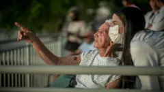 Un anciano en una silla de ruedasd junto a una doctora apunta con su mano al infinito