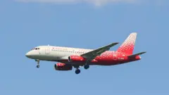 سفید اور سرخ رنگ کا روسیا سخوئی سپر جیٹ 100 روس کے شہر سینٹ پیٹرز برگ کے پلکووو ائیرپورٹ پر اترنے کی تیاری کر رہا ہے