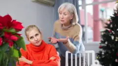 Mãe repreende filha adulta durante visita ao lar de idosos no Natal.