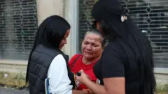 Carmen Farfán (C), madre del detenido José Gregorio Reyes, y Narwin Gil (I), hermana de la detenida Marilyn del Valle Gil, en las afueras de El Helicoide en Caracas, Venezuela, el 10 de enero de 2026.