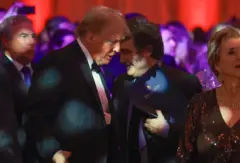 Trump e Milei vestidos com traje de gala e conversando bem próximos