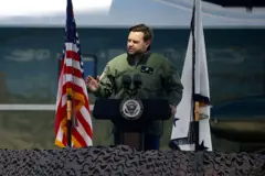 J.D. Vance discursando para fuzileiros navais, com a bandeira americana ao lado