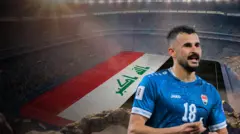صورة مركبة لاعب المتخب العراقي أيمن حسين رقم 18 قميص أزرق وخلفه علم العراق على مساحة أرض ملعب في استاد كرة قدم مليئ بالجمهور