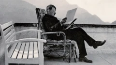 هتلر يجلس على كرسي، بينما يقرأ بعض الأوراق، التي يحملها بيديه 