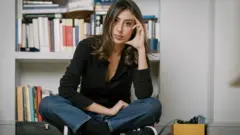 Cecilia Sala, evinde kamerelara yerde bağdaş kurmuş bir şekilde oturarak poz veriyor