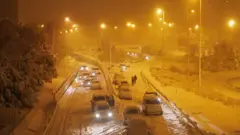 People walk after leaving their vehicles on a road in Madrid
