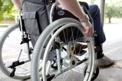 Pessoa sentada na cadeira de rodas com as mãos nas rodas