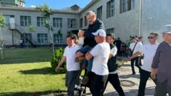 Саясатчы Азимбек Бекназаровду тарапташтары соттун имаратынан көтөрүп баратат