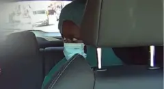 Umuntu aboneka mu maso, yambaye agafukamunwa, ari ku ntebe y'inyuma muri taxi