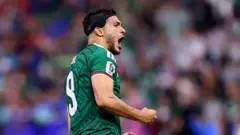Mexico's Raul Jimenez, wearing a distinctive black headband which covers part of his right temple, celebrates scoring a goal for Mexico in the World Cup