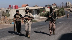 Trois membres armés des forces de sécurité syriennes marchent le long d'une route à Suweida.