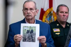 Homem idosobetfair novos clientesterno azul marinho segura página com fotografia impressa, que mostra duas bolsas e um rifle