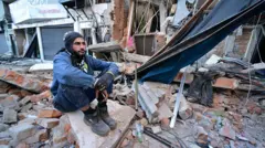 un hombre sentado sobre un conjunto de escombros en la ciudad de pereira, colombia, tras el terremoto de 7,4 ocurrido el lunes 10 de este 2026