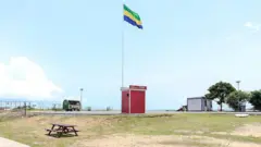 Une baraque sur laquelle est issé le drapeau gabonais sur une plage.