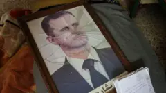 Um porta-retrato quebrado com a fotodayz cbetBashar al-Assad caído no chão