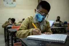 Menino em sala de aula com máscara e face shield