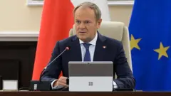 Дональд Туск за столом перед мікрофоном