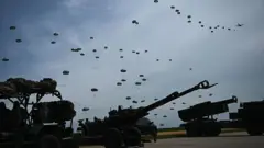 ABD ordusuna bağlı paraşütçü askerler, 10 Haziran 2025'te Başkan Donald Trump'ın Kuzey Carolina'daki ABD üssüne yaptığı ziyaret sırasında düzenlenen bir askeri gösteri kapsamında uçaktan atlıyor. 