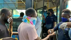 Les passagers embarquant dans un bus à Lagos reçoivent un désinfectant pour les mains