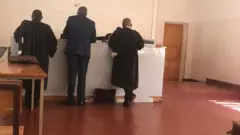 Dr Isaac Munyakazi (uri hagati) imbere y'urukiko rwisumbuye rwa Nyarugenge kuri uyu wa gatatu