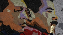 Un hombre camina junto a un mural con la imagen de Hugo Chávez y Nicolás Maduro.